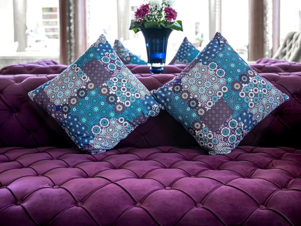 Rumors Amethyst collection cushions on a tufted purple sofa
